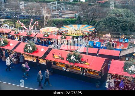 Une partie du marché de Noël et une partie de la fête foraine manèges qui font partie d'Édimbourg Noël dans l'Est des jardins de Princes Street. Contient les deux sont sur la principale ligne de chemin de fer en haut de la photo, waltzers et un carrousel sont au milieu et vers l'avant de l'image, et à l'avant de l'image sont certains des étals du marché de Noël vente de cadeaux, chocolat chaud Gluhwein, etc. Les gens se promènent entre et brosing à les étals du marché. Banque D'Images