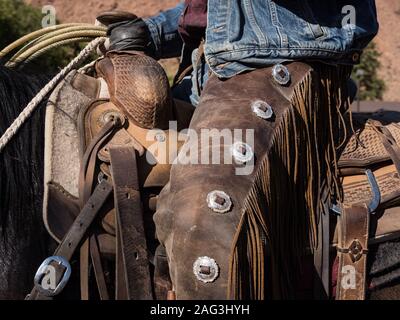 Close up detail d'un cow-boy's chaps et selle. Les chaps en cuir protéger les jambes du cowboy de brosse épineuse sur la gamme. Red Cliffs Ranch, près de M Banque D'Images