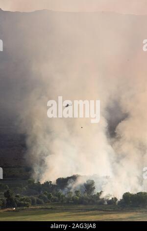 Un hélicoptère descend l'eau pour combattre un incendie qui brûle dans le Nature Conservancy Scott M. Matheson Wetlands Réserver près de Moab, Utah. Banque D'Images
