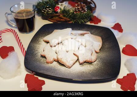 Décoration de table de Noël avec le sucre versé gingerbread cookies et café servis pour le petit-déjeuner entouré d'arbres et de décoration en bois rouge coeur Banque D'Images