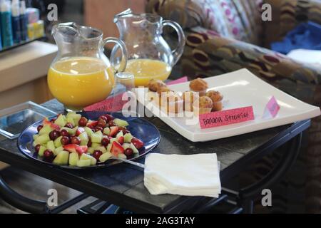 Table avec une assiette de salade de fruits et petits gâteaux et deux pots de jus d'orange Banque D'Images