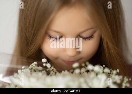 Gros plan de la fille blonde aux yeux clos bénéficiant d''un bouquet de fleurs sauvages blanches Banque D'Images