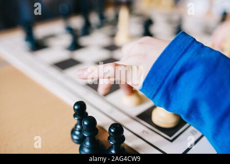 Gros plan d'un bras humain dans un chemisier bleu déplacement des figures d'échecs sur un bureau d'échecs Banque D'Images