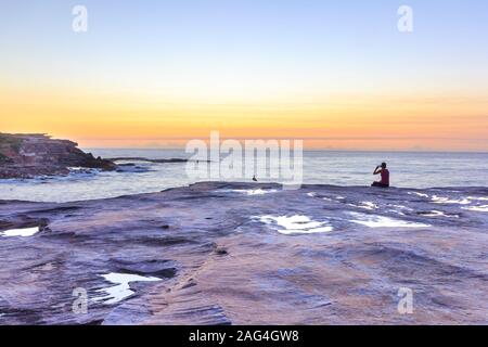 Silhouette d'une personne de prendre une photo d'un lever et d'oiseaux, Coogee, Sydney, Australie Banque D'Images