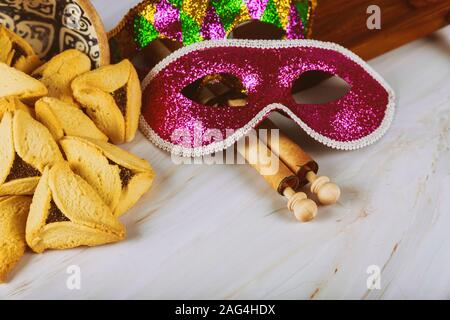 Traditionnel Pourim avec hamantaschen cookies, crécelle et masque de carnaval sur fond sombre Banque D'Images