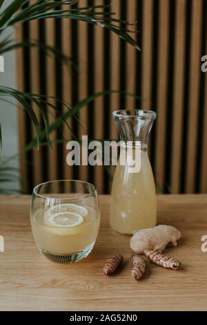 Plan vertical d'un pot et d'un verre rempli de limonade et quelques gingers sur une table en bois Banque D'Images