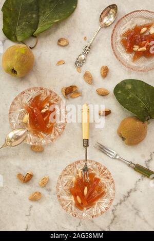 Photo grand angle de bols en verre avec confiture de coing et amandes sur une surface blanche Banque D'Images