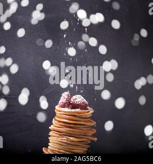 Pile de crêpes à la framboise sur le dessus. Dessert maison. Maslenitsa concept. Fond gris foncé. Le tamisage du sucre en poudre. Square et certains bokeh Banque D'Images