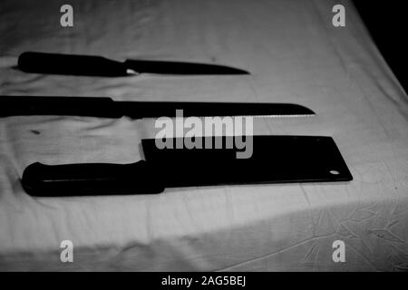 Gros plan de différents types de couteaux sur une barre de coupe en noir et blanc Banque D'Images