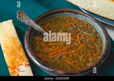 Soupe de lentilles et pain au fromage. Bol de soupe aux lentilles végétarien à la carotte, l'oignon et l'ail. Servi avec du fromage maison délicieux pain. Close up on Banque D'Images