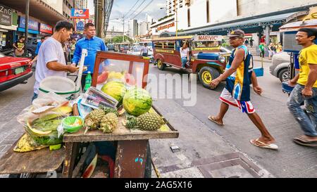 Manille, Philippines - 20 novembre, 2013. Un homme d'ananas et de pastèque de vendre son mobile location stand de fruits sur le bord d'une rue animée de Manille. Banque D'Images