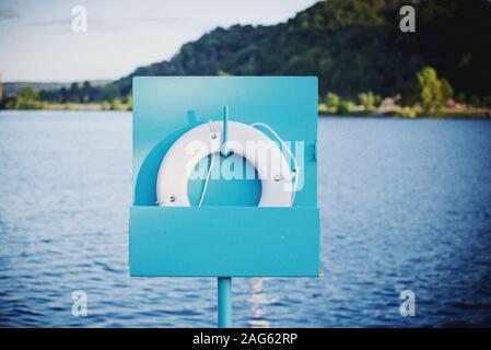 Gros plan d'une bouée de sauvetage placée sur une colonne bleue Et la mer en arrière-plan - SOS concept Banque D'Images