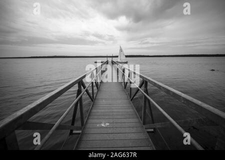 NORMAN Maine, États-Unis - Jul 07, 2018 : un coup de gris d'une jetée en bois dans l'océan avec un seul bateau dans le sombre ciel nuageux Banque D'Images