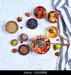 Petit-déjeuner sain et des produits pour le petit-déjeuner, le gruau avec des fruits et petits fruits, figues, bleuets, fraises, graines de lin et de chia, le miel. Vue d'en haut Banque D'Images