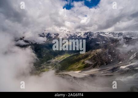 Vue aérienne de la petite ville, montagnes couvertes de neige et nuages Banque D'Images