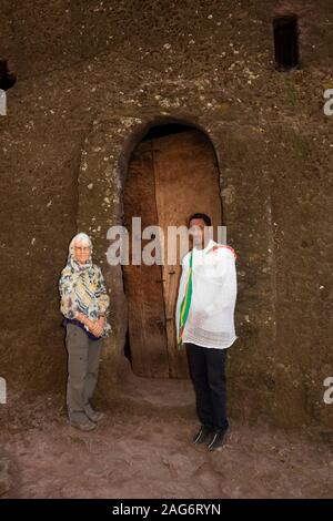 L'Éthiopie, l'Amhara, Lalibela, anciennes églises, Bet Medhane Alem église, senior woman tourist avec guide à la porte Banque D'Images