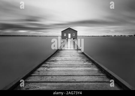 Prise de vue en niveaux de gris d'une route en bois menant à un seul maison - concept du monde imaginaire Banque D'Images