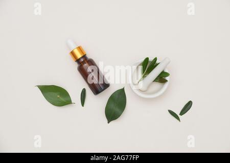 Spa concept avec des bouteilles d'huile essentielle avec de petites feuilles, .sel dans bol sur fond blanc. Banque D'Images