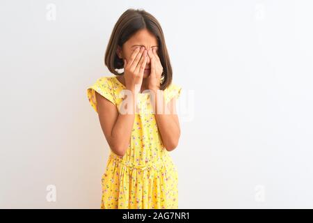 Belle jeune fille enfant portant robe jaune sur fond blanc isolé permanent se frotter les yeux pour la fatigue et maux de tête, somnolence et fatigue Banque D'Images