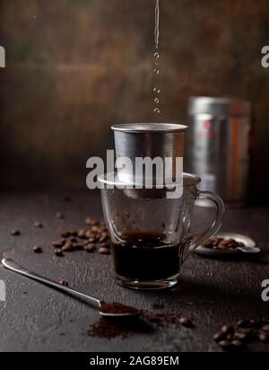 Préparation du café vietnamien avec l'aluminium cofe filer sur fond sombre Banque D'Images