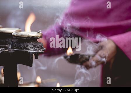 Gros plan d'une personne éclairant des bougies avec un flou arrière-plan Banque D'Images