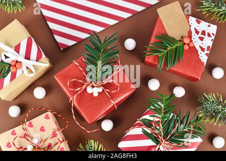 Vue de dessus du beau rouge, blanc et brun naturel boîtes cadeau de Noël décoré avec des rubans et branches de sapin sur fond brun with copy space Banque D'Images