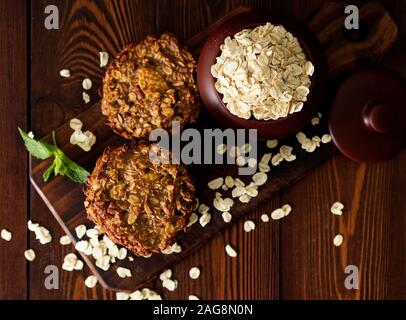 Biscuits à la maison avec la banane, l'avoine, les noix, les œufs et la farine gratuitement sur une table en bois foncé marron, vue du dessus. Banque D'Images