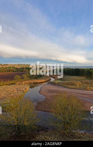 La rivière sinueuse doucement Lunan elle-même à travers les collines et les terres agricoles derrière Lunan Bay sur la côte est de l'Ecosse en décembre. Banque D'Images