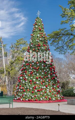 Photo verticale d'un magnifique arbre de Noël avec des ornements colorés dans un parc Banque D'Images