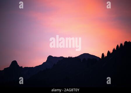 Un magnifique coucher de soleil rouge foncé avec forêt de pins et montagnes dans les Alpes françaises près de Montriond Portes du Soleil France Banque D'Images