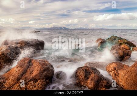 Mer Méditerranée se briser sur les rochers à Platja des Calo près de Betlem et Colonia de Sant Pere avec Cap de Formentor en arrière-plan, ciel bleu et blanc Banque D'Images