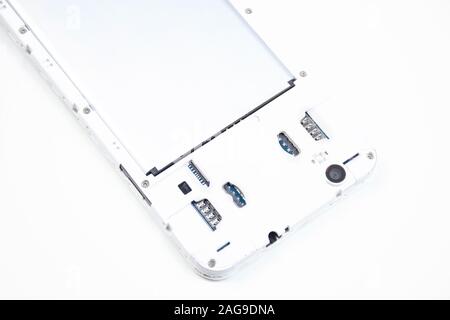 Un téléphone cellulaire avec un capot ouvert se trouve face vers le bas sur un fond blanc. Service de réparation de téléphone cellulaire. Banque D'Images