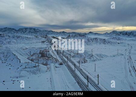 Golmud. Le 15 décembre, 2019. Photo aérienne prise le 15 décembre 2019 montre les voies du chemin de fer Dunhuang-Golmud Saishiteng près de montagne dans le nord-ouest de la Chine. Un nouveau chemin de fer reliant la ville de Dunhuang, dans le nord-ouest de la Chine, la province de Gansu et Golmud city, dans le nord-ouest de la Chine, la province du Qinghai, complètement ouvert, mercredi, selon China Railway. Les 671 km qui est une importante ligne de liaison entre le chemin de fer Qinghai-Tibet et le fer Lanzhou-Xinjiang. Il permet aux trains de fonctionner à 120 km par heure, a déclaré la société. Credit : Zhang Long/Xinhua/Alamy Live News Banque D'Images