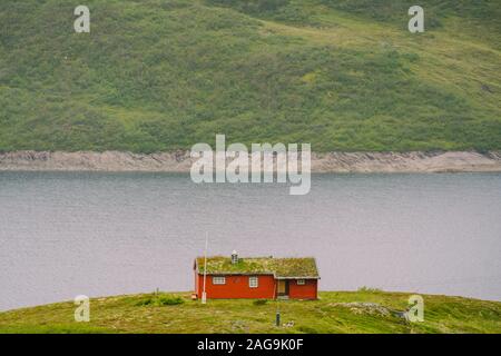 En bois norvégienne maison d'été donnant sur le lac pittoresque, Norvège, Scandinavie. Chalet au bord du lac en milieu rural. Cabane au toit de tourbe sur le lac. Au toit d'herbe typique Banque D'Images