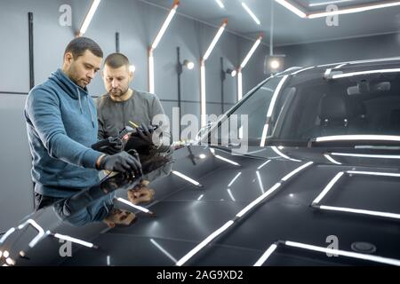 Location de deux travailleurs de l'inspection de véhicule, la mesure de l'épaisseur du recouvrement de peinture de la carrosserie du véhicule à la boîte de service. Prendre une voiture pour Détaillant professionnel Banque D'Images