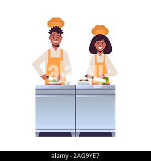 Deux cuisiniers cuisiniers professionnels couper des légumes frais à découper african american man woman restaurant travailleurs dans la préparation des aliments cuisson uniforme salade concept télévision vector illustration pleine longueur Illustration de Vecteur