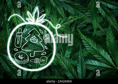 Noël arrière-plan créatif à partir de feuilles de chanvre, de la marijuana et d'un néon de collecte de jouets. Mise à plat Banque D'Images