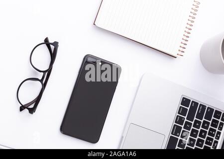 Prise de vue en grand angle d'un smartphone, d'un ordinateur portable, de lunettes et d'un ordinateur portable sur une surface blanche Banque D'Images
