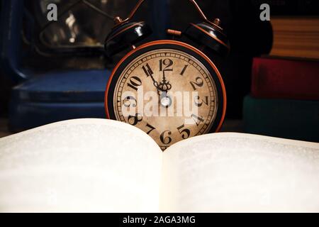 Ancienne rétro réveil en intérieur rustique avec des livres et lampe à kérosène.Close up. Banque D'Images