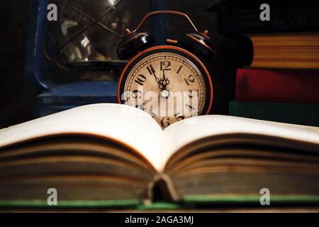 Ancienne rétro réveil en intérieur rustique avec des livres et lampe à kérosène.Close up. Banque D'Images