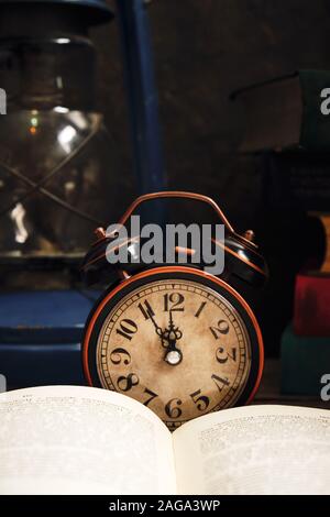 Ancienne rétro réveil en intérieur rustique avec des livres et lampe à kérosène.Close up. Banque D'Images