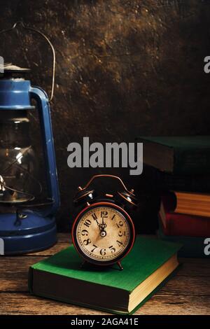 Ancienne rétro réveil en intérieur rustique avec des livres et lampe à kérosène.Close up. Banque D'Images