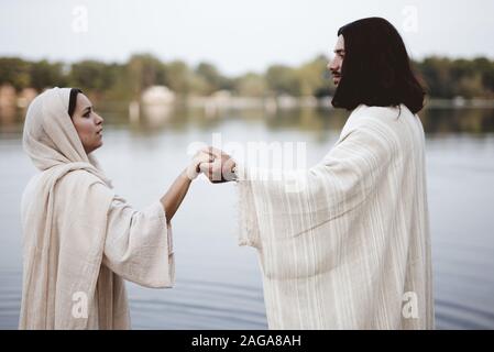 Photo d'une femelle portant une robe biblique avec mise au point peu profonde Et tenant la main de Jésus-Christ Banque D'Images