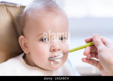 Manger une cuillère de bébé mange de la bouillie de lait Banque D'Images