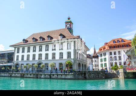 Thun, Suisse - 8 août 2019 : beau paysage urbain de la ville suisse. Maisons médiévales situées le long de la rivière Aare turquoise. Les gens à pied par le canal. Jour d'été ensoleillé. Les destinations de voyage. Banque D'Images