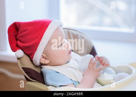 Tout-petit mange à table dans un chapeau de Noël Banque D'Images