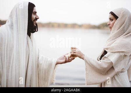 Photo d'une femelle portant une robe biblique avec mise au point peu profonde Saisir le pain de la main de Jésus-Christ Banque D'Images