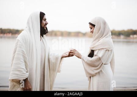 Photo de foyer peu profond de Jésus Christ donnant un morceau de pain à une femelle portant une robe biblique Banque D'Images