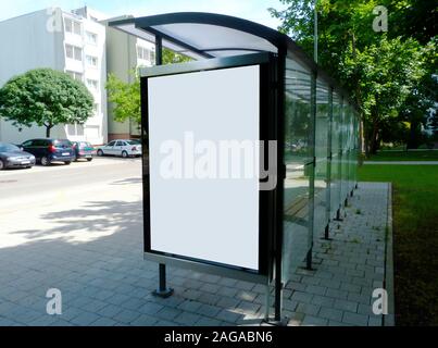 Structure en verre abri bus le long du trottoir de la rue. vert pelouse et arbres. scène d'été. blanc panneaux publicitaires. annonce l'espace. concept de commercialisation. Banque D'Images