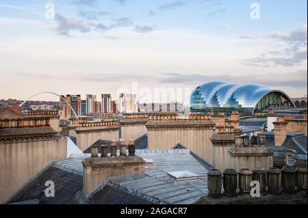 Les toits et les pots de cheminée de Newcastle upon Tyne avec courbes de l'architecture futuriste Sage Gateshead au loin. Banque D'Images